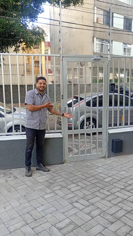 Técnico da WL Tecnologia e Segurança ao lado de portão social com fechadura elétrica e interfone instalados em Salvador